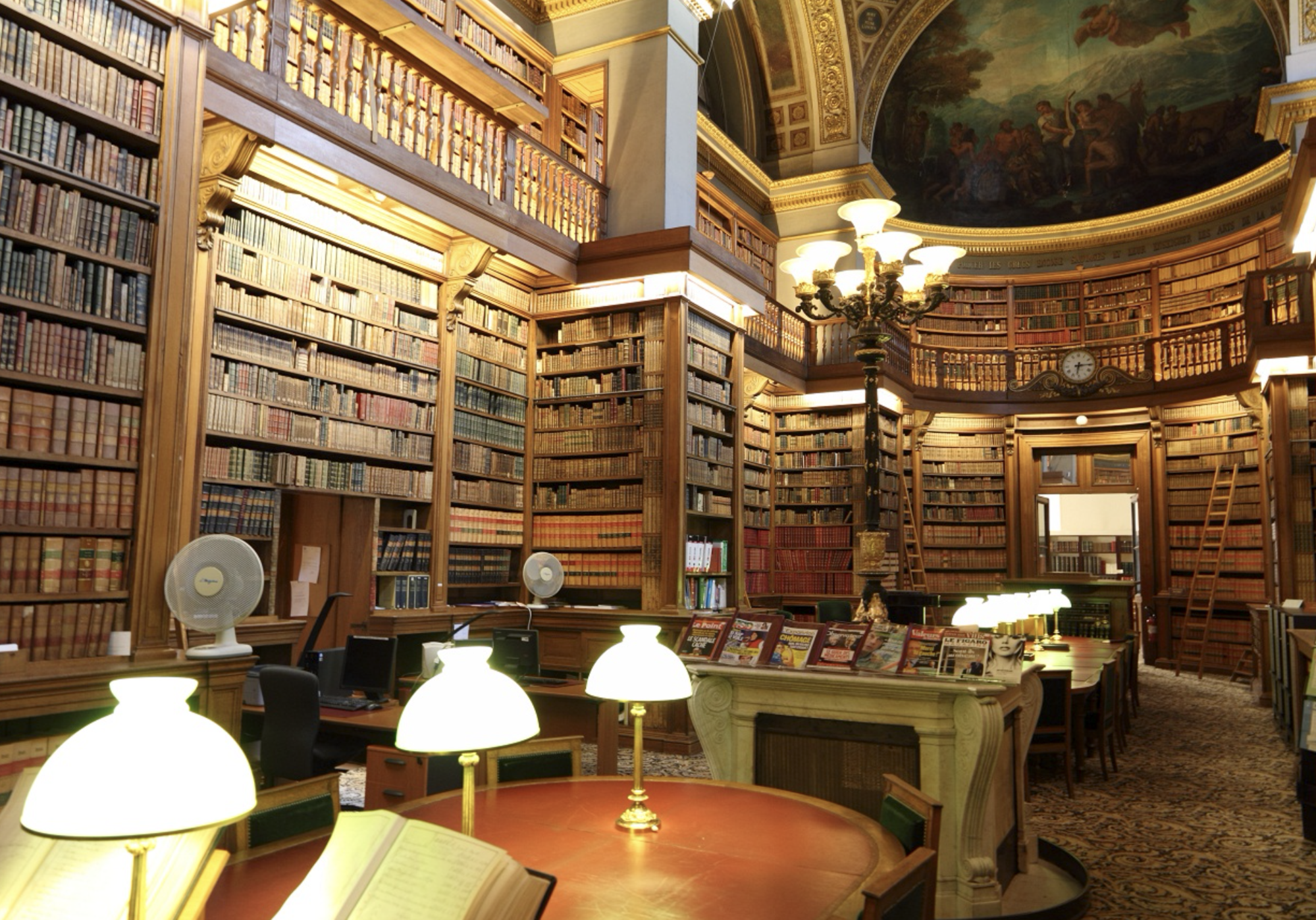 A lavish library with books lining the walls, with elegant woodwork and domed ceilings